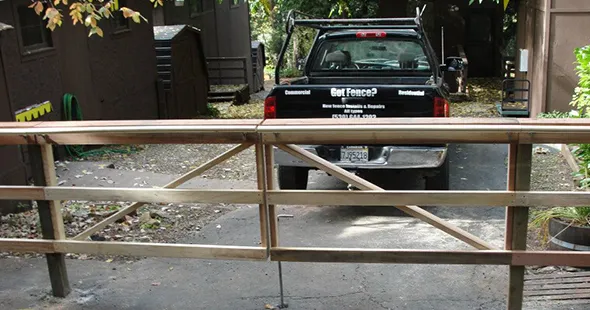 A truck stands in front of a wooden gate, representing a company specializing in fencing solutions.