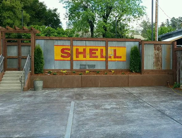 A Shell gas station located in San Francisco, surrounded by city fences and urban architecture, showcasing a bustling environment.