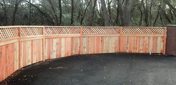 A wooden fence featuring a decorative lattice top, providing both privacy and an aesthetic appeal to the outdoor space.