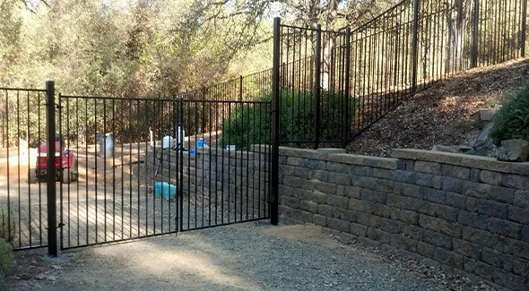 A wrought iron fence is positioned next to a solid stone wall, showcasing a harmonious combination of materials and styles.