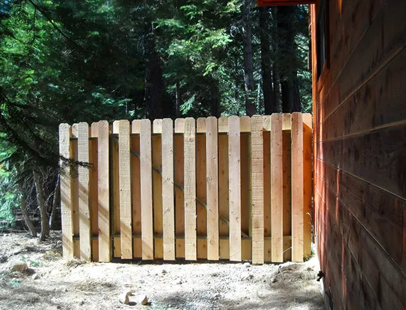 A wooden railing positioned beside a house, serving as a decorative element and functional boundary akin to fences.
