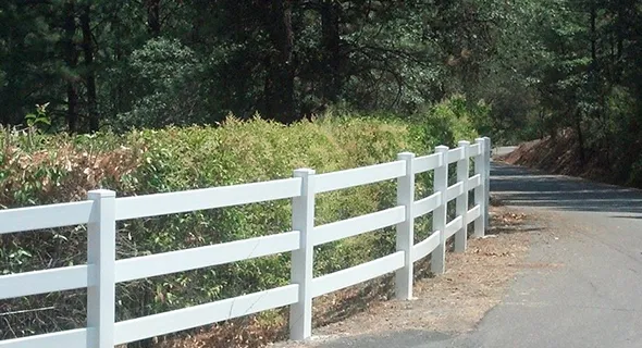 A white vinyl fence lines the side of a road, providing a clean and modern boundary to the surrounding area.
