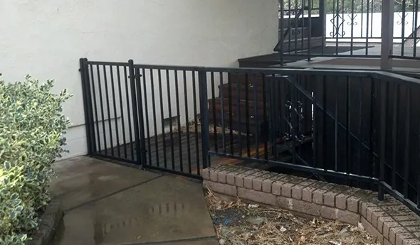 A black wrought iron fence stands elegantly beside a building, enhancing the architectural features of the surrounding area.
