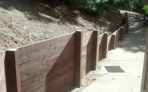 Construction of a retaining wall on a hillside highlights the essential role of fencing services in ensuring structural integrity.
