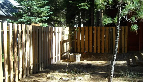 A wooden fence encloses the backyard of a residence, showcasing the benefits of expert fencing services for home security.