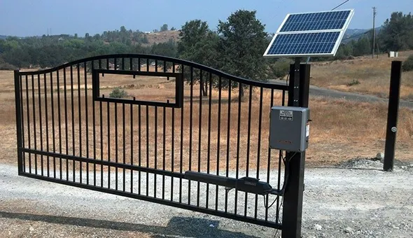 A wrought iron fence gate featuring a solar panel, showcasing a blend of traditional design and modern energy solutions.