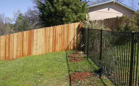 A well-installed fence stands in front of a house, bordered by a neatly maintained lawn.