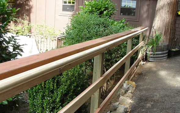 A wooden railing adjacent to a house, enhancing the property’s aesthetic while providing a boundary similar to fences.
