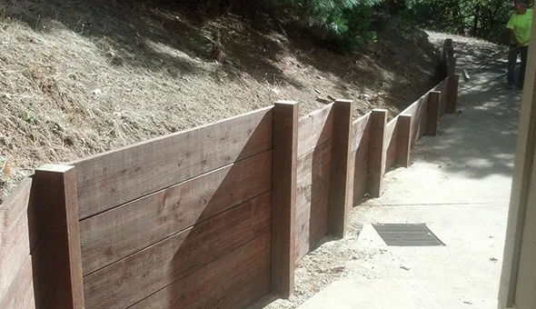 Construction of a retaining wall on a hillside highlights the essential role of fencing services in ensuring structural integrity.