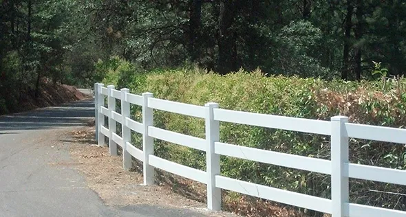 A white vinyl fence lines the side of a road, providing a clean and modern boundary to the surrounding area.