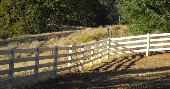 A white fence stands prominently in the center of a vast field, showcasing effective fencing solutions for open spaces.