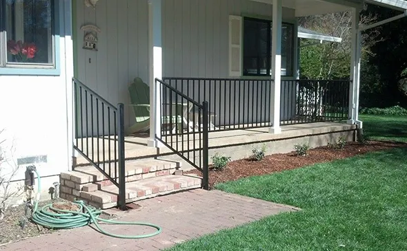 A charming porch with a wrought iron railing and steps, providing access to the entrance of a lovely home.